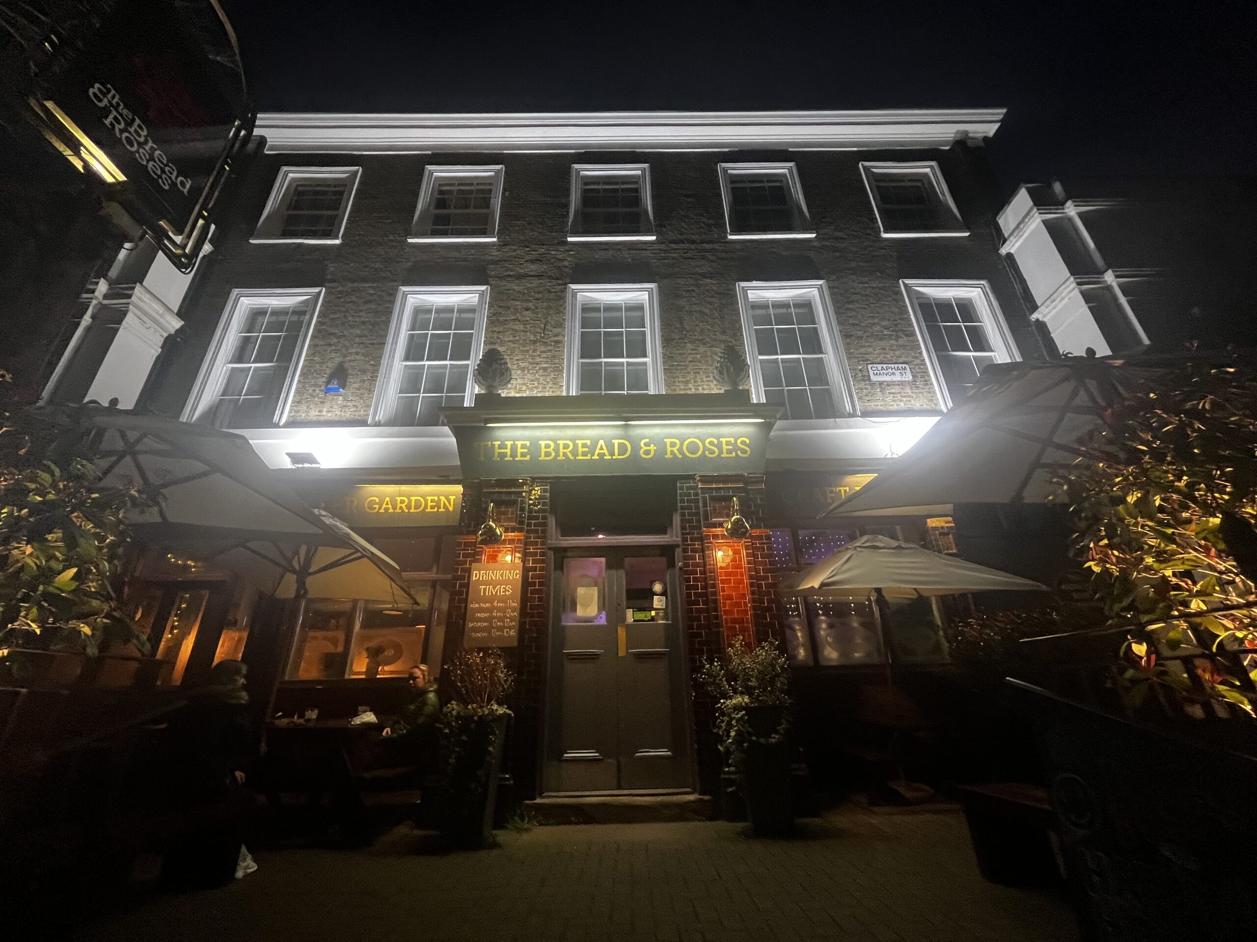 The Bread & Roses frontage on Clapham Manor Street at night